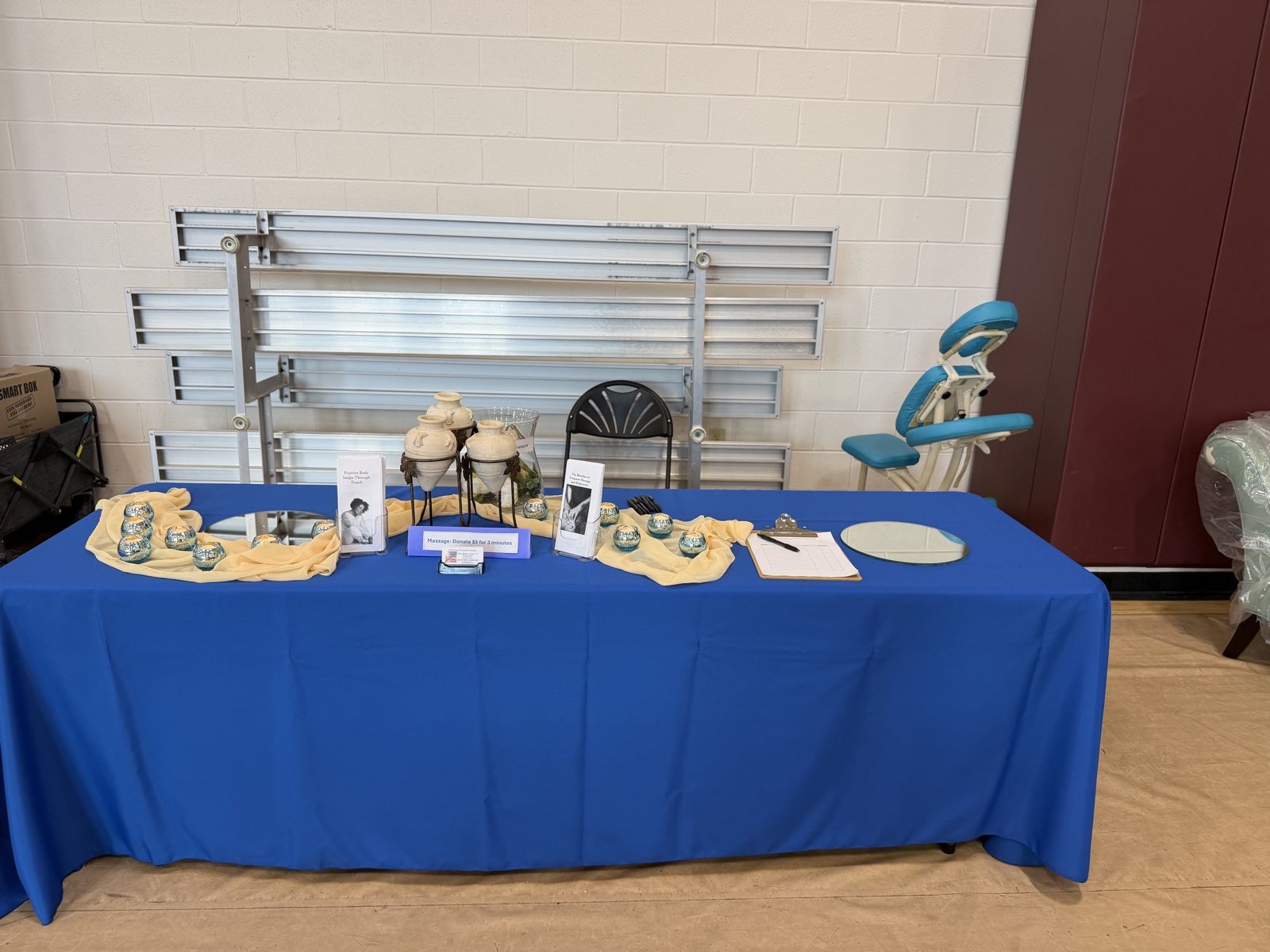 The Gifted Touch table set up at an event with body care products and a massage chair