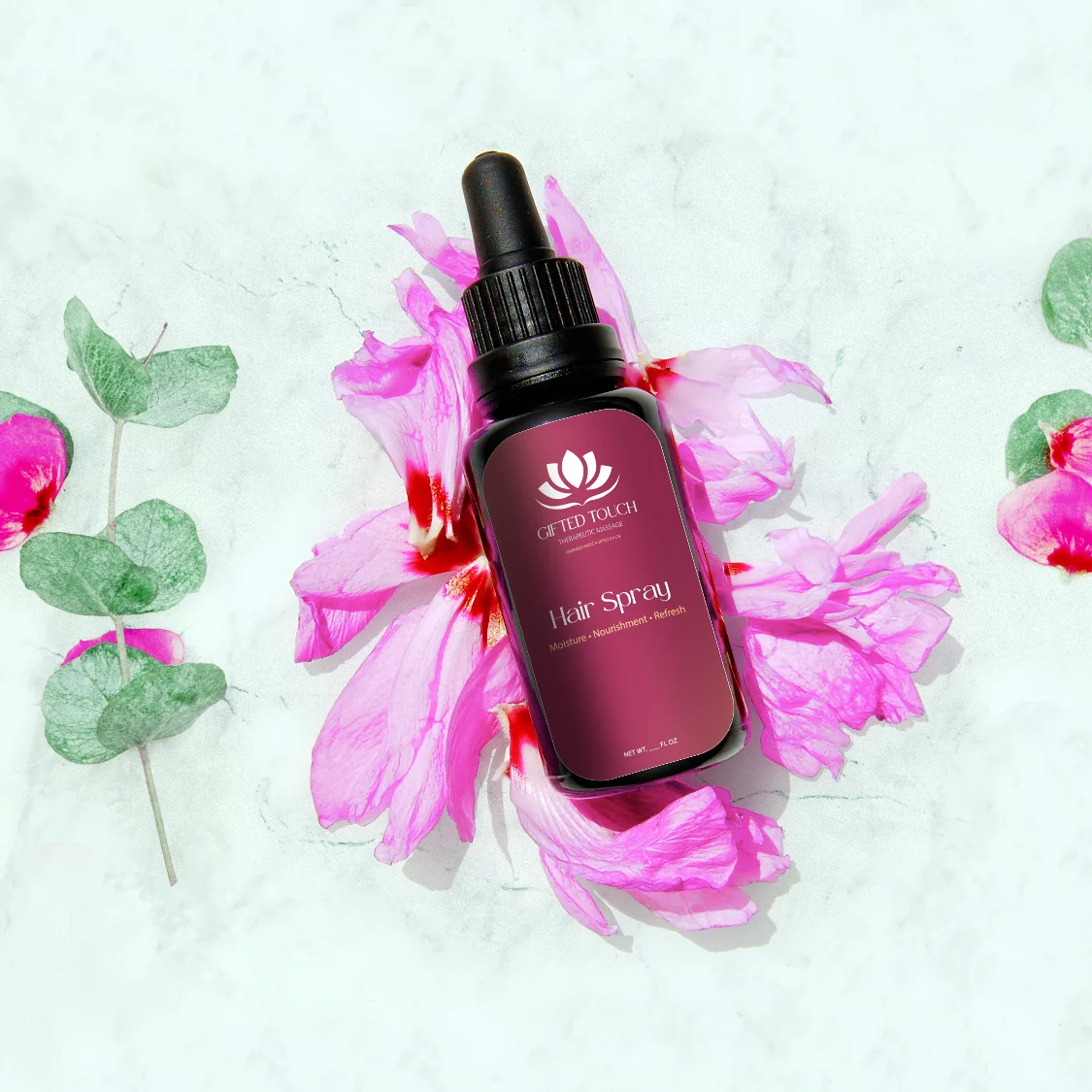 Gifted Touch Hair Spray in its new label, styled on marble with pink flowers