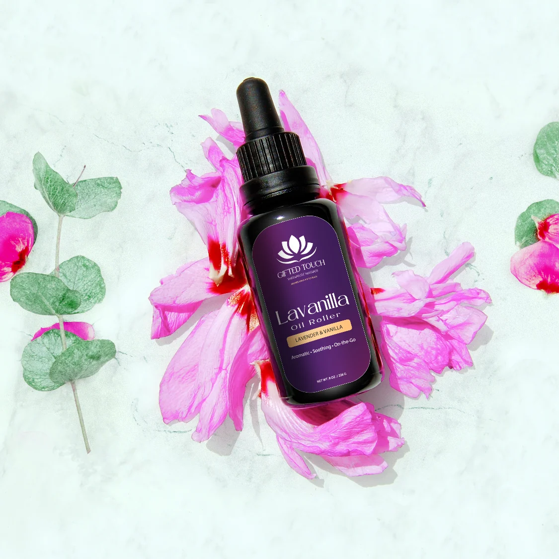 Lavanilla Oil Roller in its new Gifted Touch label, styled on marble with pink flowers
